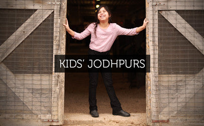 A girl in saddle seat jodhpurs in a horse barn